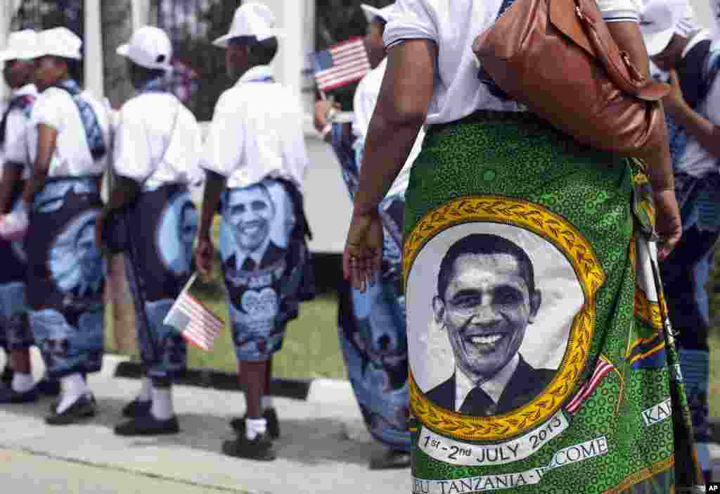 Meninas e mulheres jovens usam cangas com a imagem do presidente dos EUA. Elas seguem em fila para o palácio presidencial em Dar es Salaam para cumprimentar Barack Obama.
