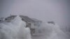 File - Waves crash over oceanfront homes during a nor'easter in Scituate, Massachusetts on January 29, 2022. 