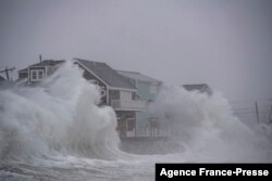 Ombak menghantam rumah-rumah di tepi pantai di Scituate, Massachusetts, 29 Januari 2022. (JOSEPH PREZIOSO / AFP)