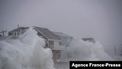 File - Waves crash over oceanfront homes during a nor’easter in Scituate, Massachusetts on January 29, 2022. 