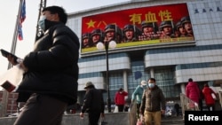 An advertisement of the People's Liberation Army overlooks a street scene in Beijing on the day Chinese President Xi Jinping and his U.S. counterpart Joe Biden hold a virtual summit, in Beijing, China, Nov. 16, 2021. 