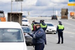 A police officer checks the ID of a person driving into Moscow at a checkpoint at the entrance to Moscow, Russia, April 15, 2020.