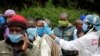 FILE - A health worker takes the temperature of a person standing in line for mass testing in an effort to stop the spread of the coronavirus disease (COVID-19) in the Kibera slum of Nairobi, Kenya, May 26, 2020. 