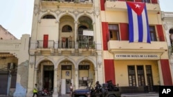 La policía de las fuerzas especiales patrulla las calles mientras pasan frente a una gran bandera cubana que cuelga de la fachada de un edificio, en La Habana, Cuba, el 21 de julio de 2021. 