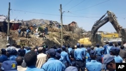 Police officers secure the perimeter at the scene of a garbage landslide, as excavators aid rescue efforts, on the outskirts of the capital Addis Ababa, Ethiopia, March 12, 2017. 