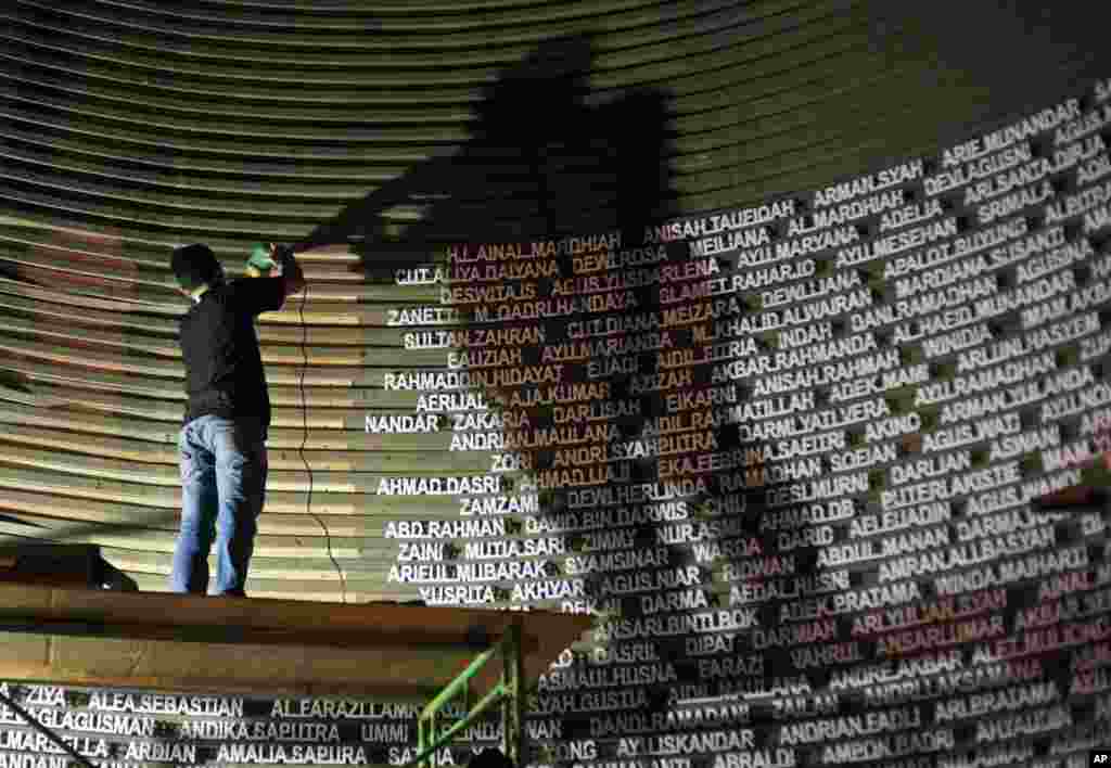 A worker installs the names of the victims of the 2004 Indian Ocean tsunami on the wall of the Tsunami Museum ahead of the 10th anniversary of the storm in Banda Aceh, Indonesia.