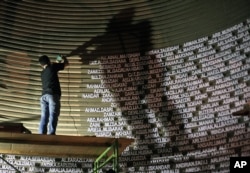 FILE - A worker installs the names of the victims of the 2004 Indian Ocean tsunami on the wall of the Tsunami Museum ahead of the 10th anniversary of the killer waves in Banda Aceh, Aceh province, Indonesia, Dec. 4, 2014.