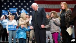 Democratic presidential candidate Sen. Bernie Sanders, I-Vt., center, is joined by his wife Jane, right, and grandchildren, Dylan, 4, and Ella, 7, on stage after speaking at a town hall at the Orpheum Theater in Sioux City, Iowa, Jan. 19, 2016.