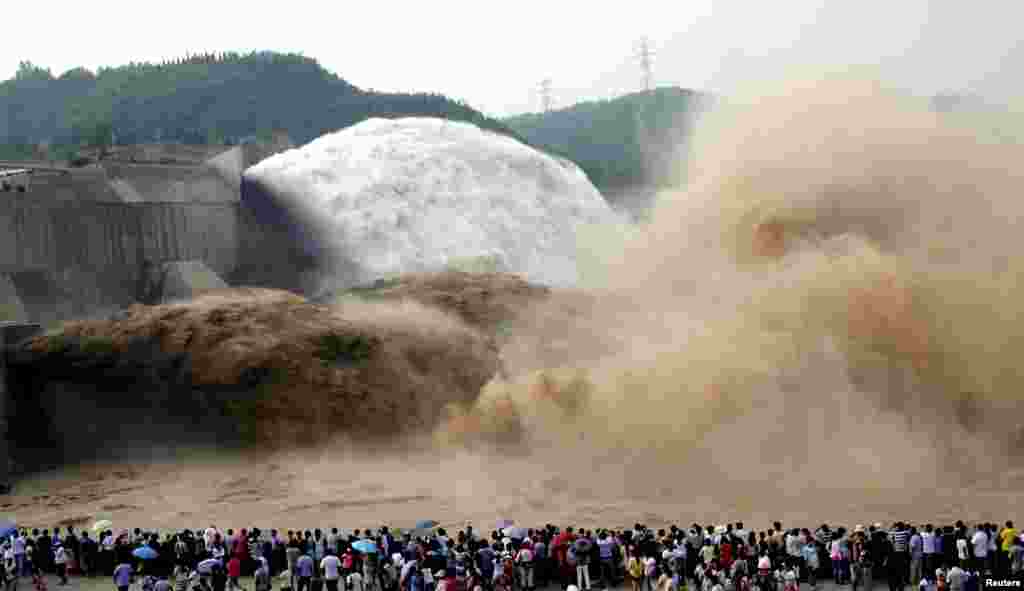 People look on as water gushes from the Xiaolangdi Reservoir section on the Yellow River, during a sand-washing operation in Jiyuan, Henan province, China, July 5, 2014.
