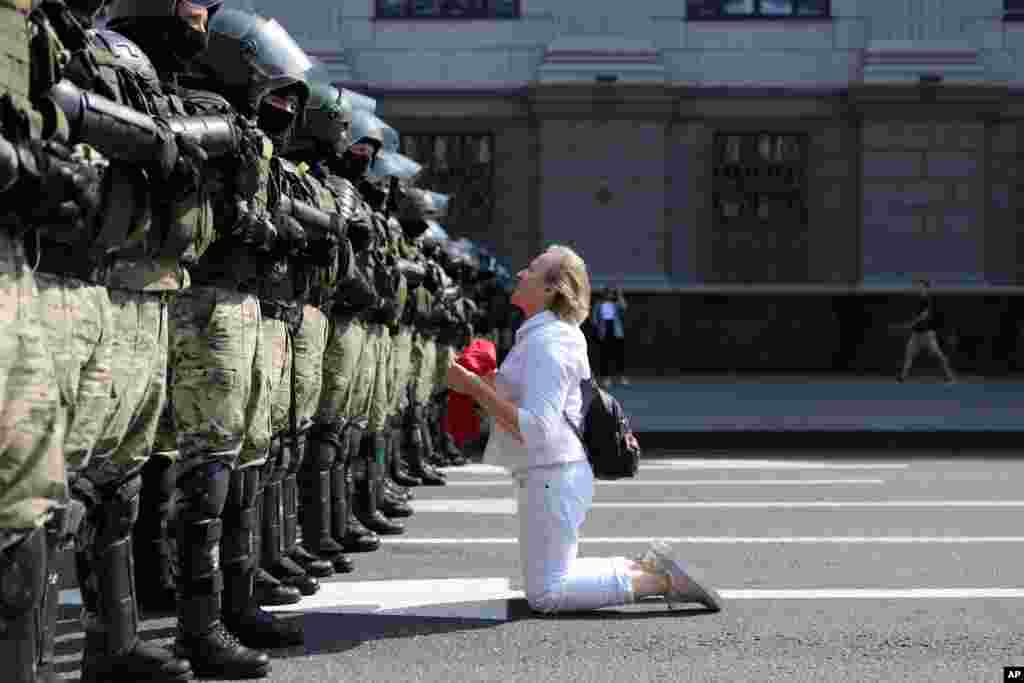 A woman kneels in front of a riot police line as they block Belarusian opposition supporters rally in the center of Minsk, Belarus.