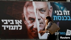 Seorang wanita berjalan melewati spanduk kampanye pemilu Partai Biru Putih yang menggambarkan pemimpinnya, Menteri Pertahanan Israel Benny Gantz, bersama Perdana Menteri Israel Benjamin Netanyahu di Tel Aviv, Israel 14 Maret 2021. (Foto: Reuters)