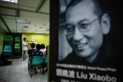 FILE - Activists hold a memorial event to mark the third anniversary of the death of Chinese dissident Liu Xiaobo, pictured at right, in Hong Kong, July 13, 2020.