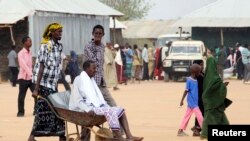 FILE - A wheelbarrow serves as transportation for the infirm and, in a poor neighborhood of Nairobi, Kenya, for women in labor. Here, a Somali man travels in Kenya's Dadaab Refugee Camp. 