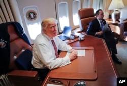 President Donald Trump, with his Chief of Staff Reince Priebus, sits at his desk on Air Force One upon their arrival at Andrews Air Force Base, Jan. 26, 2017.