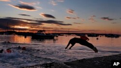 FILE - A long-distance swimmer dives into the Atlantic Ocean at dawn, July 24, 2015, in Falmouth, Maine. 