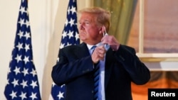 Arhiva - Predsednik SAD Donald Tramp skida sa lica zaštitnu masku, u Beloj kući, Vašington.