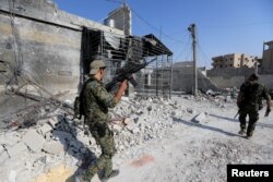 Members of the Syrian Democratic Forces walk at their position during fighting with Islamic State militants in Nazlat Shahada, a district of Raqqa, Syria, Aug. 16, 2017.