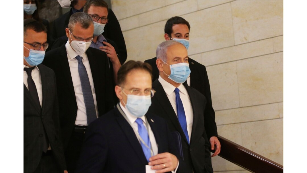 El primer ministro israelí, Benjamin Netanyahu, segundo a la derecha, usa una máscara facial protectora, mientras se dirige a la ceremonia de juramentación de su nuevo gobierno, en el Knesset, el parlamento de Israel, en Jerusalén.