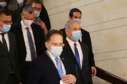 El primer ministro israelí, Benjamin Netanyahu, segundo a la derecha, usa una máscara facial protectora, mientras se dirige a la ceremonia de juramentación de su nuevo gobierno, en el Knesset, el parlamento de Israel, en Jerusalén.