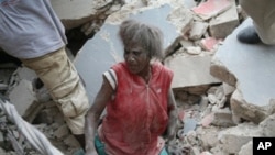 A Haitian woman is helped from the rubble of a damaged building, 12 Jan 2010, in Port-au-Prince after a huge earthquake measuring 7.0 rocked the impoverished Caribbean nation