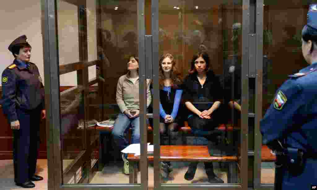 Para anggota Pussy Riot duduk di ruangan kaca pada pengadilan di Moscow (10/10). (AP/Sergey Ponomarev)