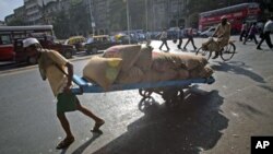 A man pulls a hand-drawn cart loaded with sacks of chickpeas on a main road in Mumbai, April 21, 2011