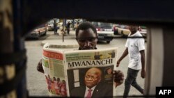 A man reads a newspaper with a headline announcing the death of Tanzania's President John Magufuli in Dar es Salaam, on March 18, 2021.