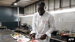 Ivorian chef Charlie Koffi prepares gouagouassou sauce with rabbit accompanied by rice in his restaurant at Villa Alvira in Abidjan on December 4, 2023.