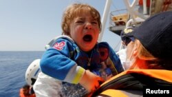 A child migrant is brought onto the Malta-based NGO Migrant Offshore Aid Station (MOAS) ship Phoenix during a rescue operation in the central Mediterranean, in international waters off the Libyan coastal town of Sabratha, May 4, 2017.