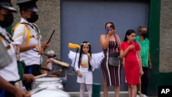 Residentes miran a la banda de música de la escuela durante un desfile de madres e hijos en un comedor de beneficencia celebrando la Navidad en el barrio Antimano de Caracas, Venezuela, el jueves 16 de diciembre de 2021.