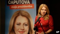 FILE - Presidential candidate Zuzana Caputova addresses the media following the first round of presidential elections, in Bratislava, Slovakia, March 16, 2019. The poster reads "Caputova is my president."