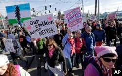 Protesters walk in a women's march that brought tens of thousands Saturday, Jan. 21, 2017, in Seattle