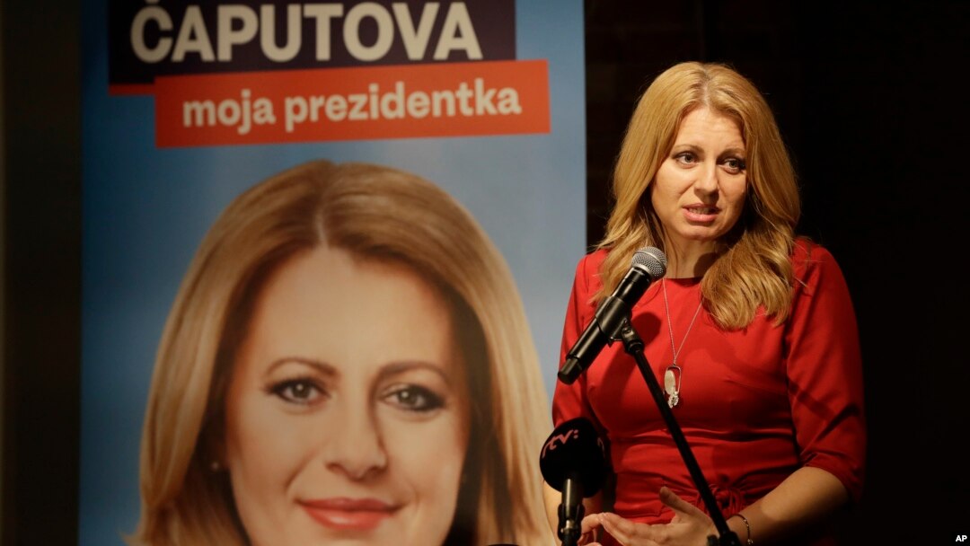 FILE - Presidential candidate Zuzana Caputova addresses the media following the first round of presidential elections, in Bratislava, Slovakia, March 16, 2019. The poster reads "Caputova is my president."