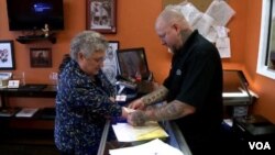 Robin Rhoderick discusses getting a medical tattoo with Jeffery Grimet, owner of Inner Soul Ink, a tattoo salon in Mount Airy, Maryland. (VOA/A. Greenbaum)