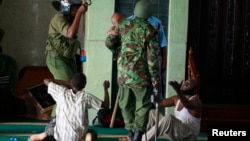 Muslim men are detained by police officers at the Masjid Mussa Mosque in the coastal town of Mombasa, Feb. 2, 2014. 
