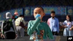Un niño chino sostiene su mascarilla mientras visita el lugar turístico de El Templo del Cielo en Beijing. Existe la preocupación en China de un nuevo brote de coronavirus.