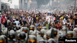 Patizan lidè opozisyon an, Henrique Capriles, an fas lapolis anti-emet pandan yo tap manifeste pou yo mande yon rekontaj vwa yo (15 avril 2013). 