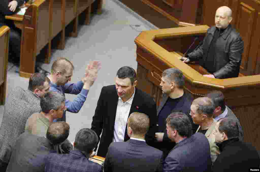 Pemimpin oposisi Ukraina dan kepala partai UDAR, Vitaly Klitschko (tengah depan) berbicara dengan para koleganya, dengan ketua parlemen baru Oleksander Turchynov (kanan atas) dalam sebuah sidang parlemen di Kyiv (22/2).