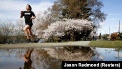 seorang wanita berlari-lari di sekitar Green Lake Park sebagai upaya jarak sosial terus membantu memperlambat penyebaran Covid-19 di Seattle, Washington, AS 29 Maret 2020. (Foto: REUTERS/Jason Redmond)