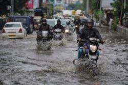 People drive through a flooded street during heavy rains in Mumbai, India, August 4, 2020.