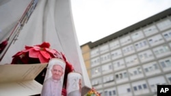 Velas con la imagen del Papa Francisco se colocan bajo la estatua del difunto Papa Juan Pablo II en el exterior del Policlínico Agostino Gemelli en Roma, el 19 de febrero de 2025, donde el Pontífice está hospitalizado desde el 14 de febrero.