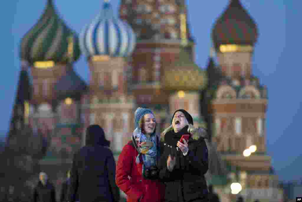 Tourists take a selfie in front of St. Basil Cathedral in Red Square in Moscow, Russia.
