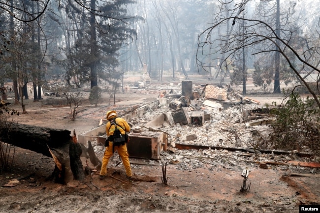 A firefighter extinguishes a hot spot in a neighborhood destroyed by the Camp Fire in Paradise, California, Nov. 13, 2018.