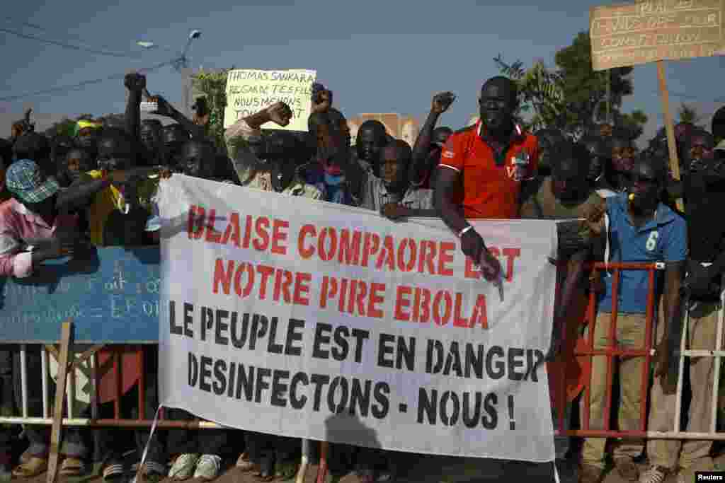 Des manifestants tiennent avec une banderole avec la mention &ldquo;Balise Compaoré est notre Ebola&nbsp;: Le peuple est en danger, désinfectons-nous&nbsp;!&raquo; à Ouagadougou, Burkina Faso, le 20 octobre 2014. &nbsp;La police a lancé des grenades à gaz lacrymogène aux&nbsp; manifestants qui ont usé des pierres à la fin d&rsquo;une manifestation qui avait regroupé des dizaines de milliers de gens. REUTERS/Joe Penney 