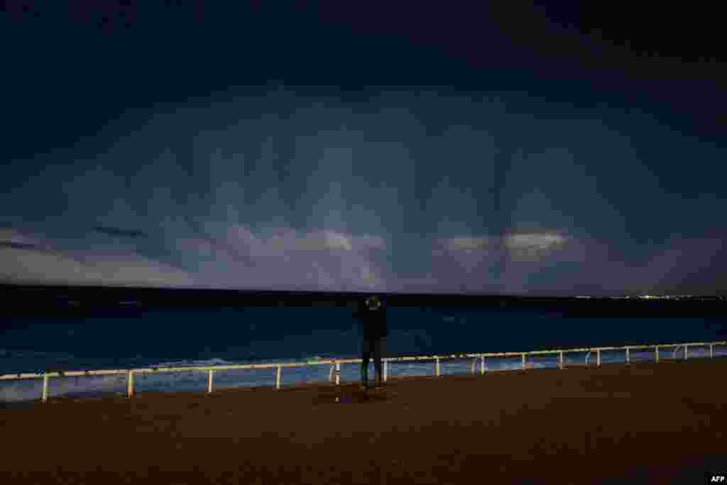 A man looks at a thunderstorm above the Mediterranean sea on the French Riviera city of Nice, Oct. 23, 2019.