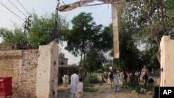 Seorang petugas kepolisian yang tidak berseragam, memotret pintu gerbang penjara yang rusak akibat serangan militan Taliban di Dera Ismail Khan, Pakistan (30/7). 