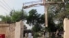 A plainclothes police officer takes a photo with his mobile phone of a damaged gate of center jail caused by Taliban militants attacked, Tuesday, July 30, 2013 in Dera Ismail Khan, Pakistan. 