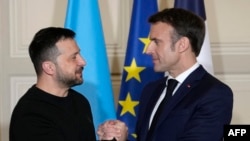 法国总统马克龙与乌克兰总统泽连斯基在巴黎爱丽舍宫签署双边安全协议后，在联合举行记者会时握手。(2024年2月16日)