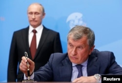 FILE - Russia's President Vladimir Putin, left, and Rosneft CEO Igor Sechin attend a signing ceremony at the St. Petersburg International Economic Forum 2014 in St. Petersburg, May 24, 2014.