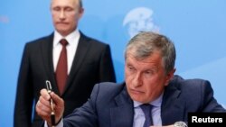 FILE - Russian President Vladimir Putin, back, and Rosneft CEO Igor Sechin attend an event in St. Petersburg, May 24, 2014. A court has authorized the U.S. to seize a Boeing 737 owned by Rosneft Oil, U.S. authorities said March 8, 2023. Sechin has been sanctioned by the U.S.